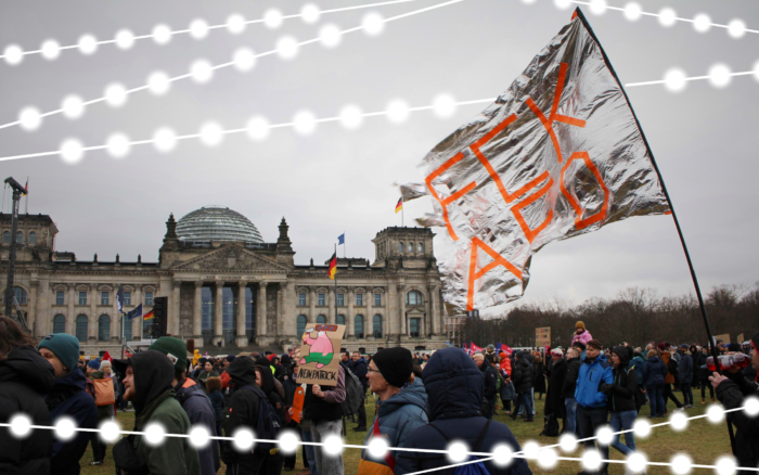 Menschenmenge an einem grauen Tag vor dem Bundestag, im Vordergrund eine große silberne Fahne mit der Aufschrift FCK AFD.