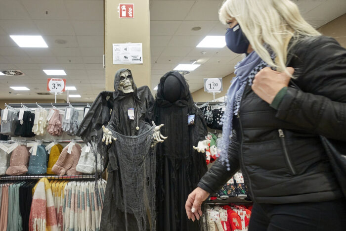 Frau läuft in einem Geschäft an Halloweenartikeln vorbei