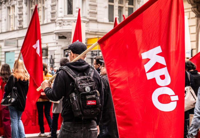 Demobild mit einigen Teilnehmenden mit roten KPÖ Flaggen