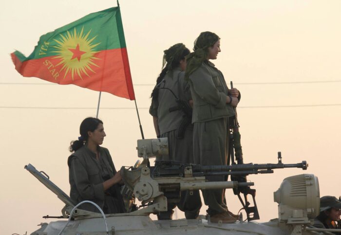 Vier kurdische Guerilla-Kämpferinnen mit der Flagge der autonomen Frauenarmee YJA Star.