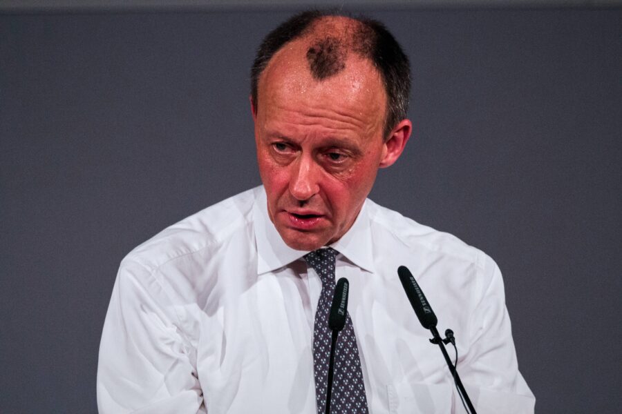 Ein schwitzender Friedrich Merz mit hochrotem Kopf steht an einem Rednerpult