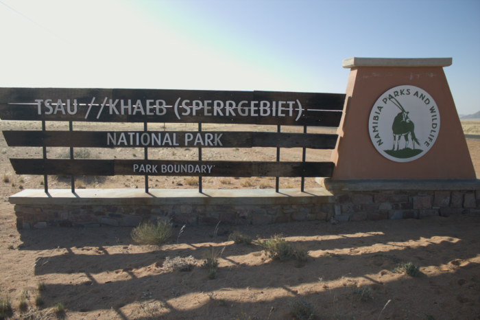 Eingang zum Nationalpark. Auf Holzbrettern steht Tsau ǁKhaeb (Sperrgebiet) National Park Grenze