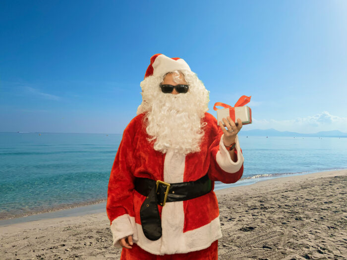 Ein Weihnachtsmann steht am Strand.