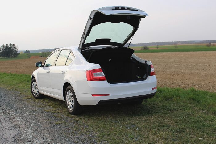 Man sieht ein weißes Auto mit geöffnetem Kofferraum.