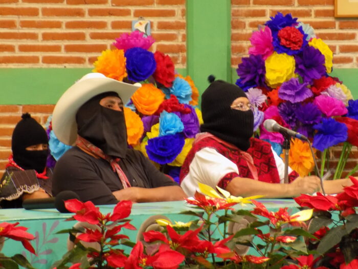 Vermummte Zapatistas auf einem Podium.