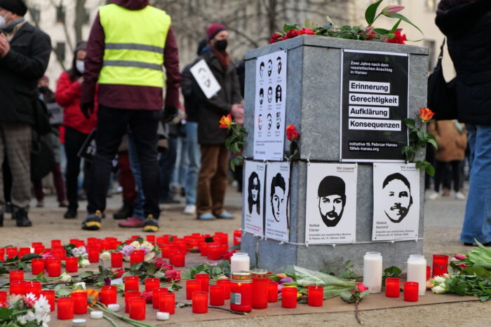 Fotos von Ferhat Unvar, Mercedes Kierpacz, Hamza Kurtovic und Vili Viorel Paun hängen auf einem Denkmal am Oranienplatz in Berlin, das umgeben von Blumen und Kerzen ist.