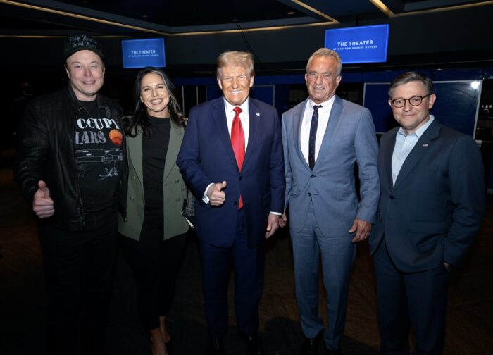 Gruppenbild im Dunklen, mit Blitz gechossen. Donald Trump, Elon Musk, Tulsi Gabbard, RFK Jr und Mike Johnson lächeln unheimlich in die Kamera