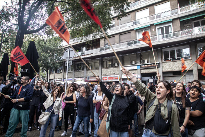 Mitglieder der Mieter*innengewerkschaft protestieren im September 2024 vor dem Parteibüro von Junts per Catalunya. Sie schwenken rote Fahnen und schreien etwas. Es sind viele junge Frauen dabei.