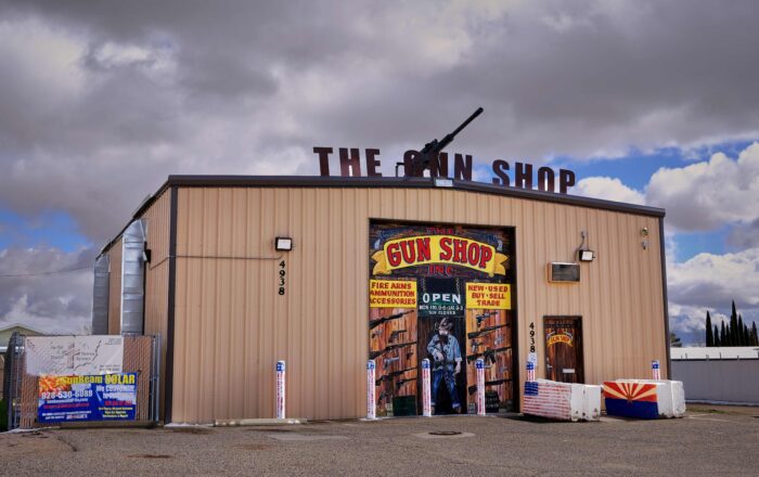 Eine kleine Blechhalle, auf deren Dach eine MG montiert ist, außerdem in Großbuchstaben "The Gun Shop". Die Pfeiler vor dem Geschäft sind in den Farben der US-Fahne bemalt