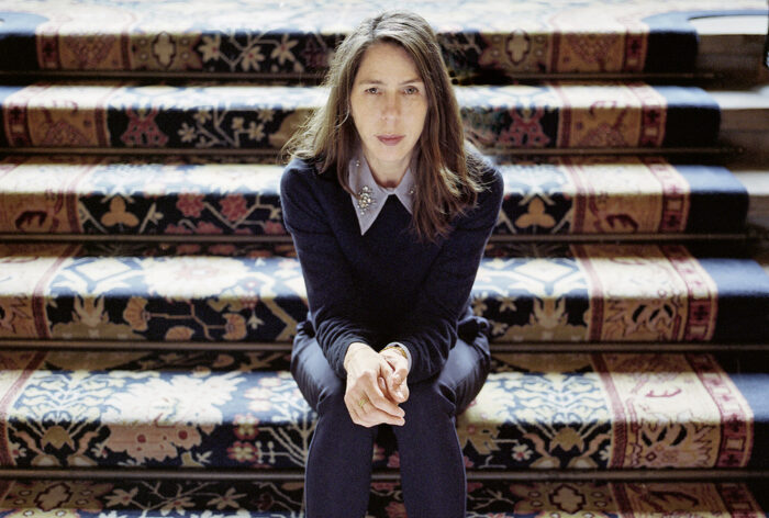 Die Autorin Rachel Kushner auf einer Treppenstufe sitzend.