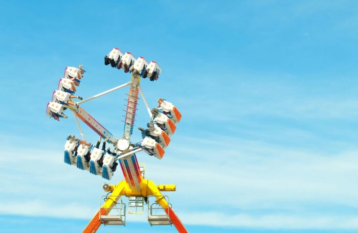 Das Bild zeigt einen vollbesetzen Shaker auf dem Rummel, der gerade in der Luft hängt. Im Hintergrund ist nur blauer Himmel zu sehen